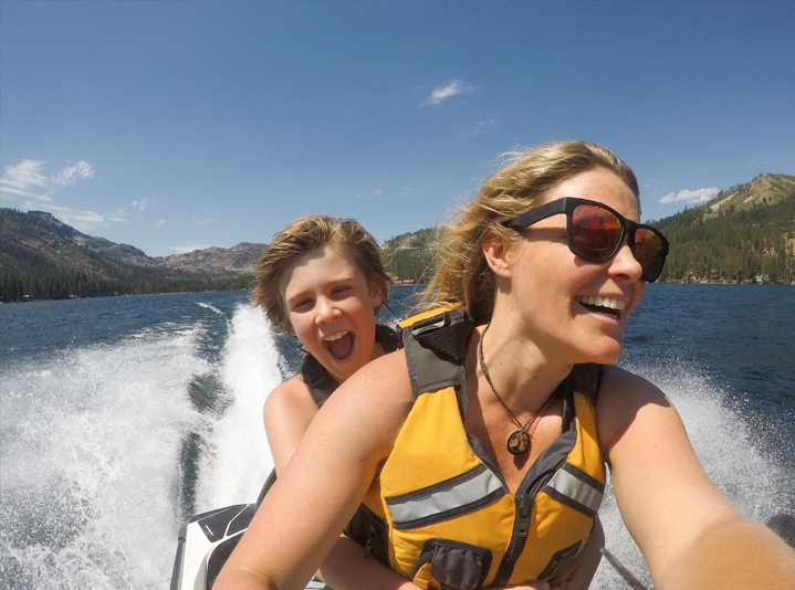 Mom and kid cruising a lake on a jet ski.