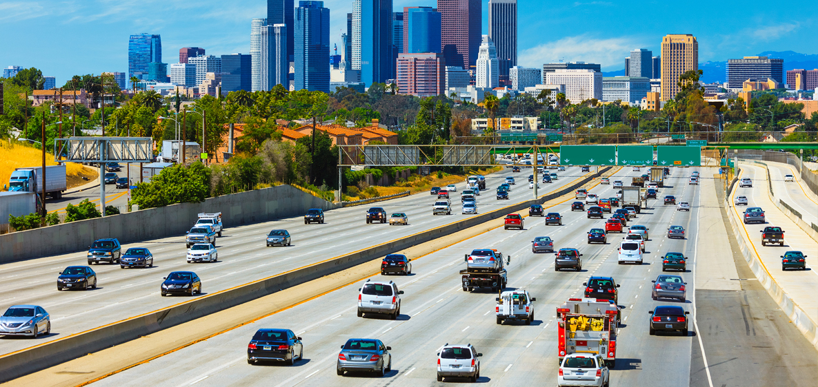 Automotive traffic powered by lead and lithium batteries with cityscape in the background.