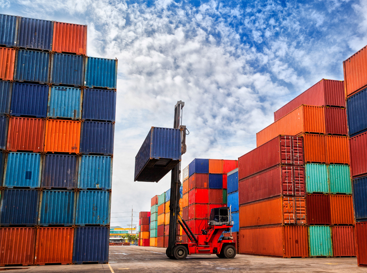 Lift truck moving shipping containers for industrial logistics.