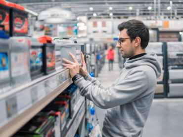 Man in a retail store purchasing a lead battery.