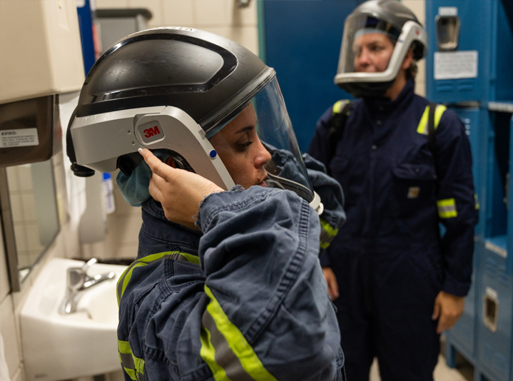 Lead battery recycling employees putting on PPE for employee safety. Lead battery recycling employees putting on PPE for employee safety.